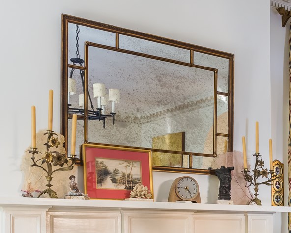 artwork and collectibles reflected in mirror over mantel